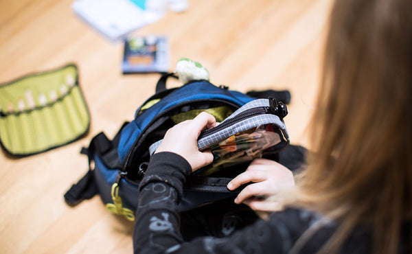 A child pulling an organizer pouch from The Sprout.